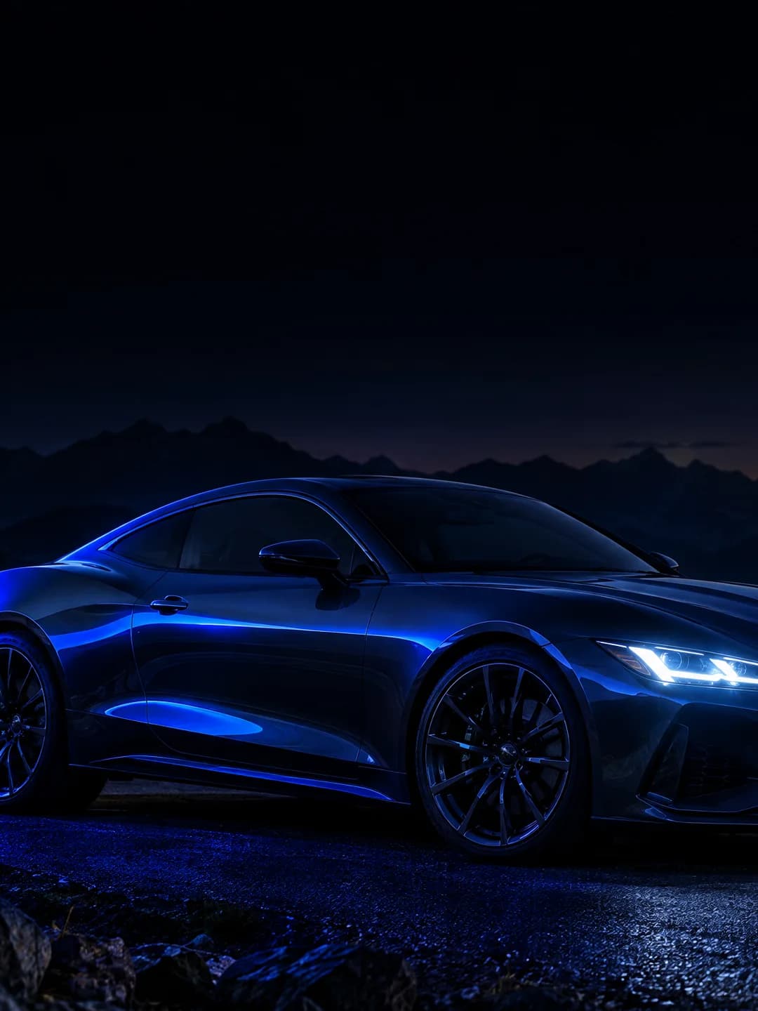 Coupé deportivo BRAND en una carretera de montaña de noche, iluminado en azul.